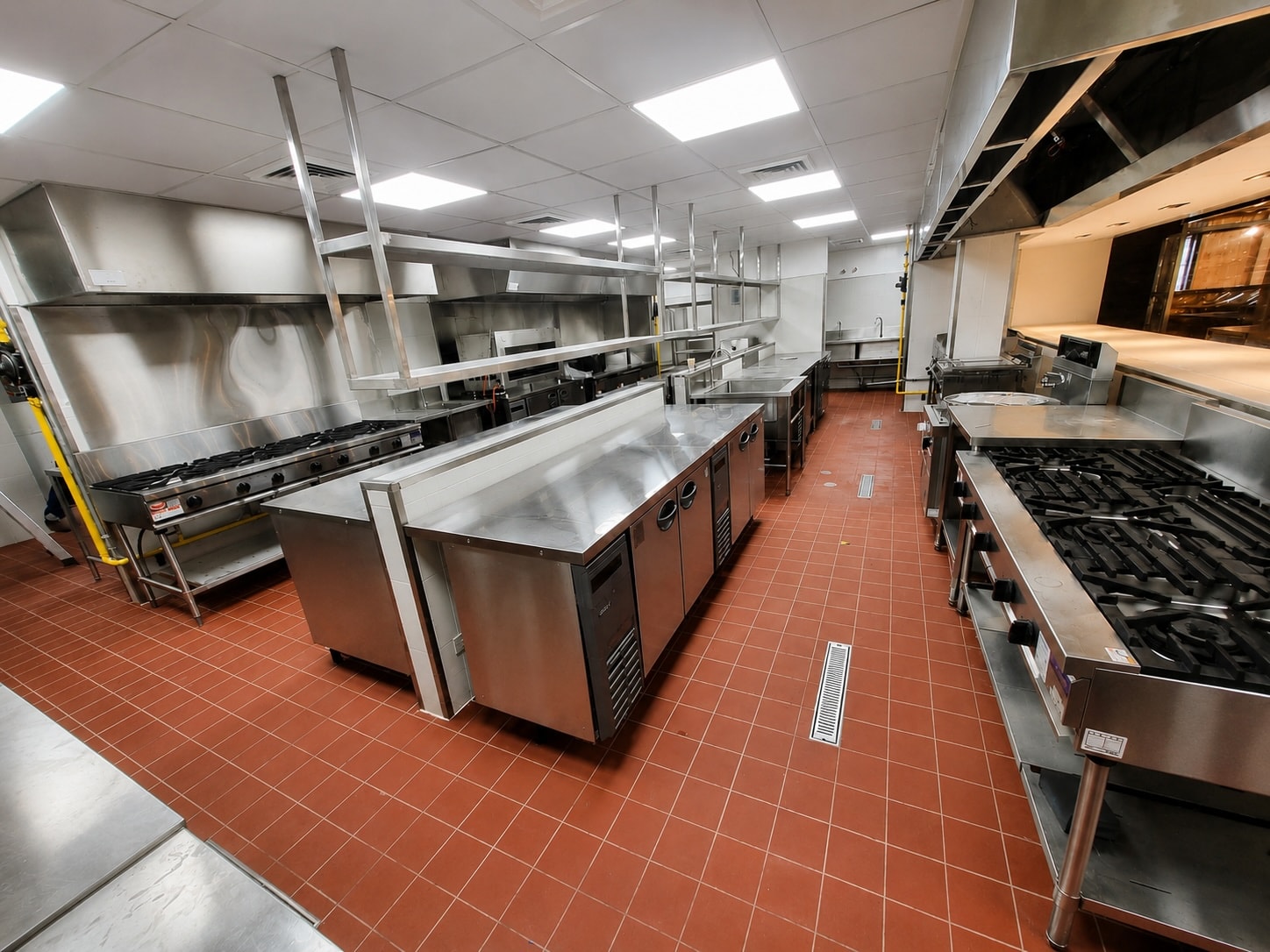 Completed commercial kitchen with stainless steel surfaces and professional equipment